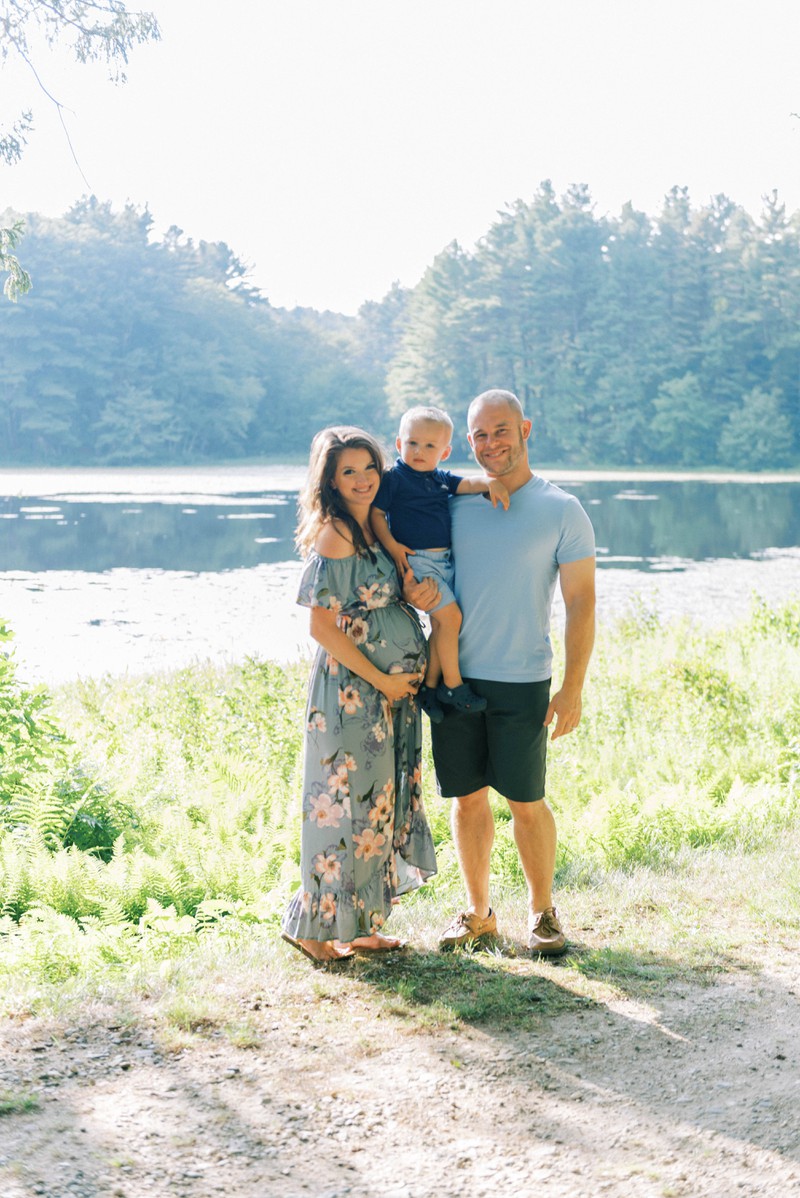 Eine dreiköpfige Familie posiert vor einem See