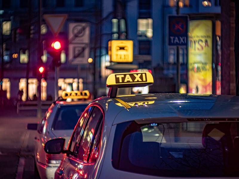 Zu sehen sind Taxis in Berlin bei Nacht.