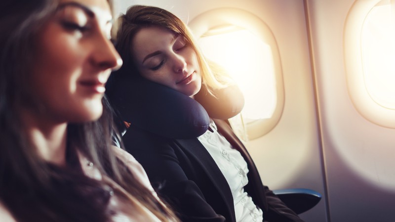 Zwei schlafende Menschen im Flugzeug sind zu sehen und es geht um Tipps beim Langstreckenflug.