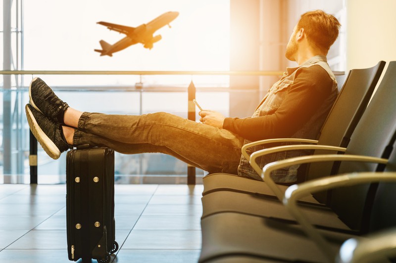 Dieses Bild zeigt einen Mann, der am Flughafen auf seinen günstig gebuchten Urlaub wartet.