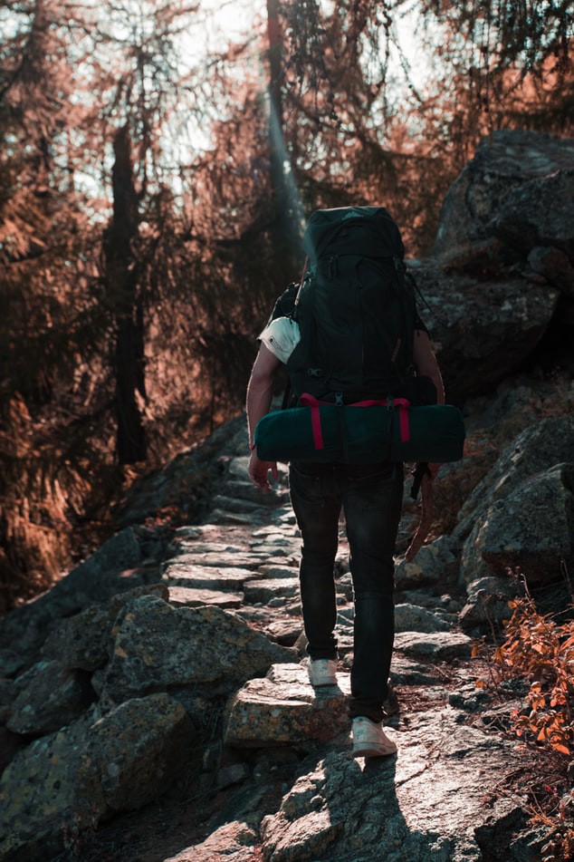 Dieser Mann trägt einen Rucksack auf Reisen, der sich einfach mit einem Packsystem ordnen lässt.