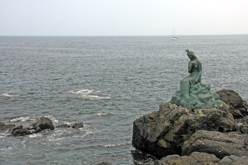 Auf den Klippen sitzt eine Bronzefigur