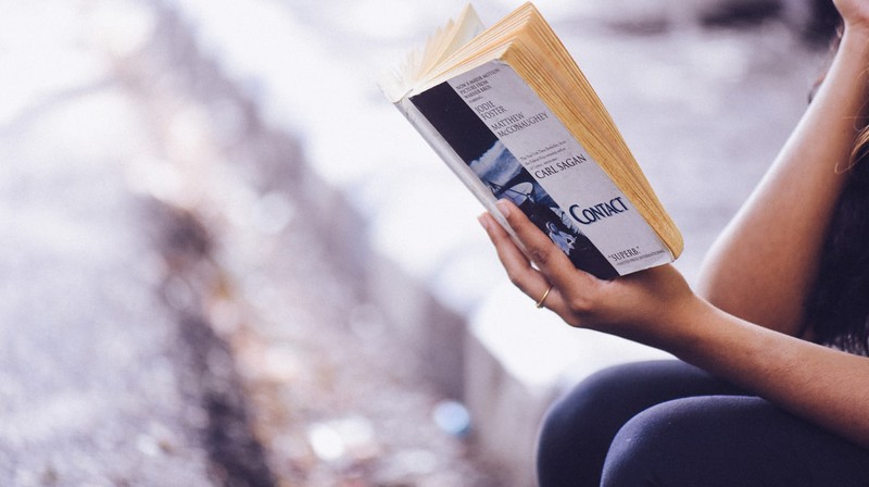 Frau, die eine digitale Auszeit nimmt und ein Buch liest