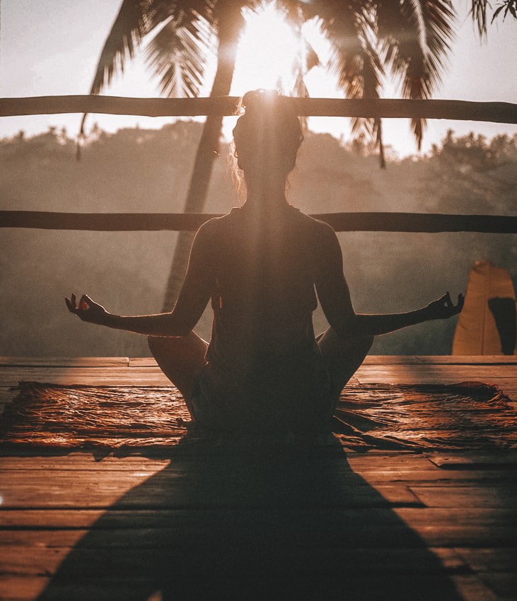 Eine Frau macht an einem Urlaubsort unter Palmen Yoga
