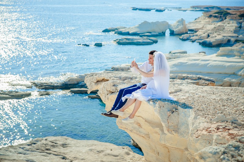 pärchen sitzt auf stein am meer