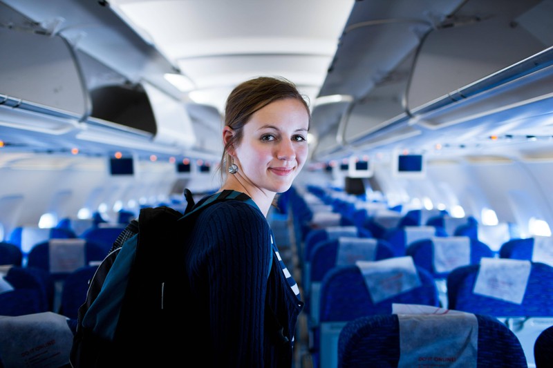 Eine junge Frau steht im Inneren eines Flugzeugs.