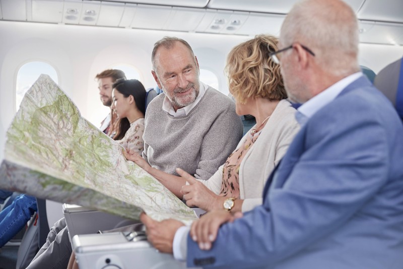 Die Menschen auf dem Foto haben auf ihrem Sitzplatz im Flugzeug wenig Platz.