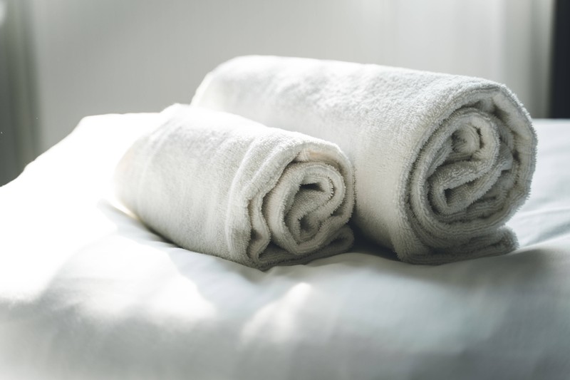 Ein Hotelbett, auf dem Angestellte Handtücher vorbereitet haben.